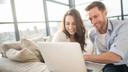 Gothaer Kapitallebensversicherung: Paar am Laptop freut sich über günstige Beiträge zur Versicherung.